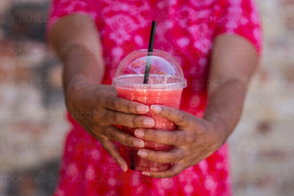 woman holding pink smoothie drink - Australian Stock Image