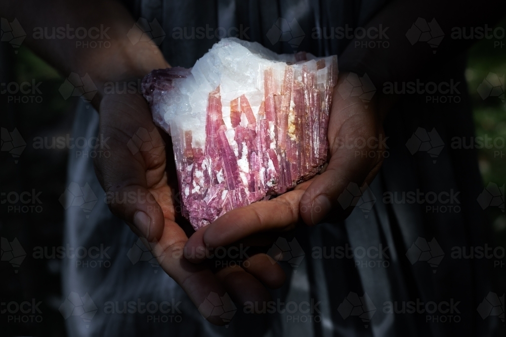 Woman holding pink tourmaline in quartz crystal in healing concept - Australian Stock Image