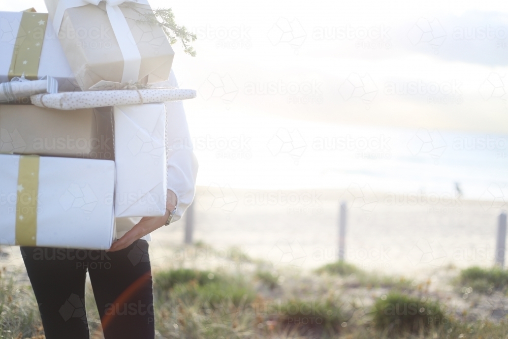 Woman holding presents at the beach in morning light - Australian Stock Image