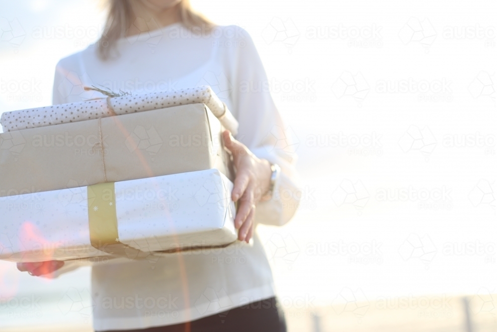 Woman holding presents with beach in background - Australian Stock Image