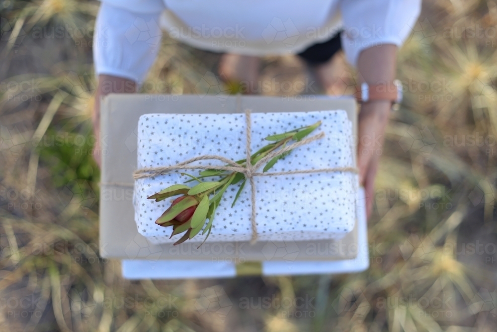 Woman holding presents with sea grass in background - Australian Stock Image
