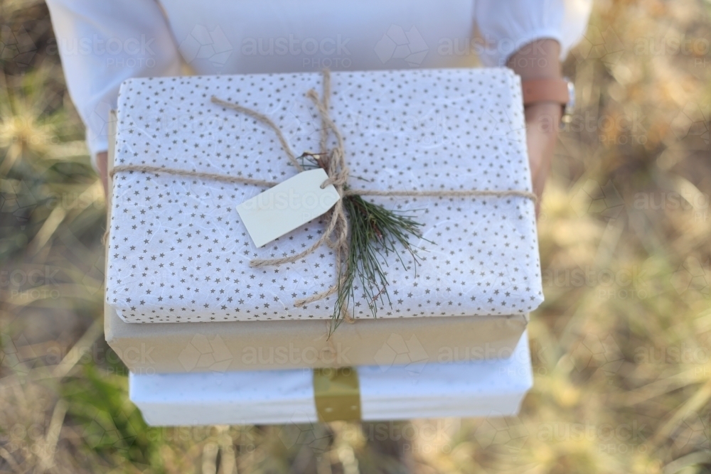 Woman holding presents with sea grass in background - Australian Stock Image