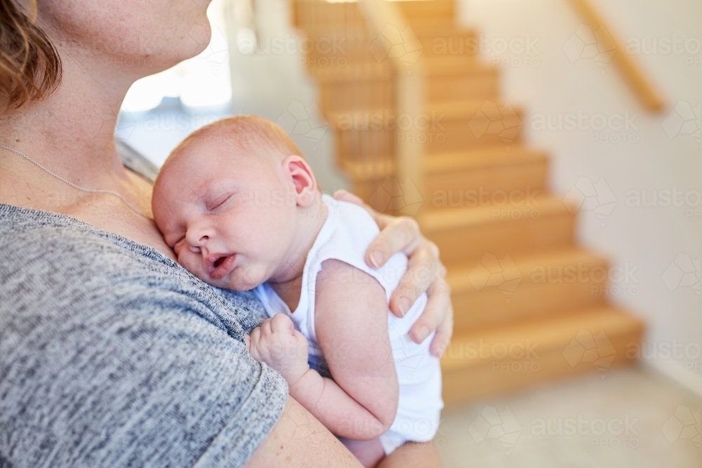 Woman holding sleeping newborn - Australian Stock Image