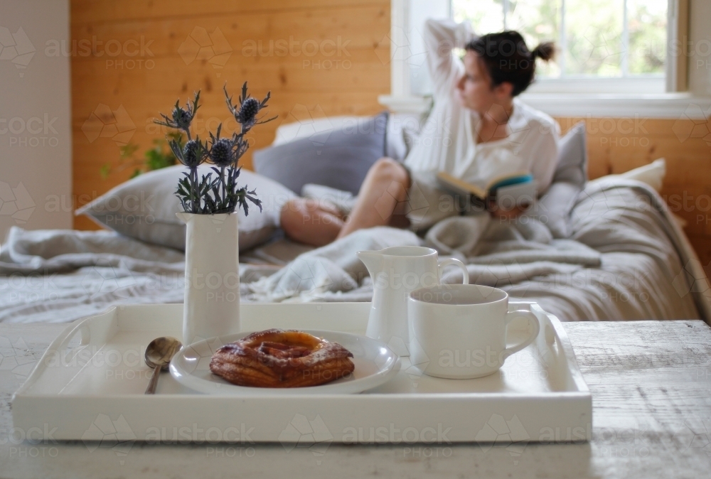 Woman in bed with breakfast tray in foreground - Australian Stock Image