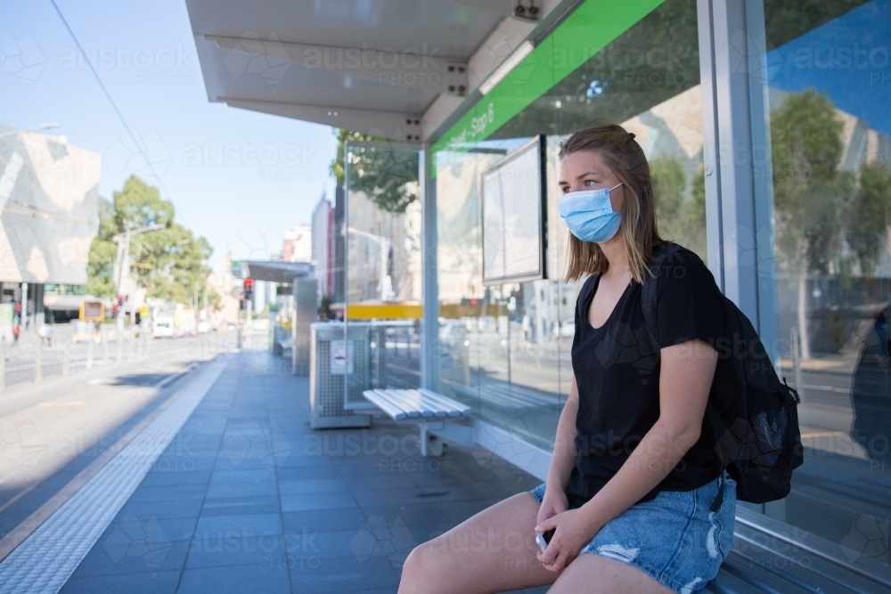 Woman in Face Mask Waits for the Tram - Australian Stock Image