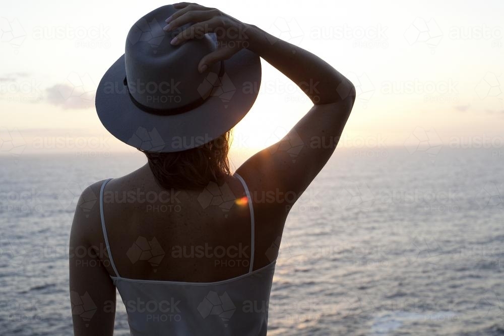 Woman in hat looking out at ocean - Australian Stock Image