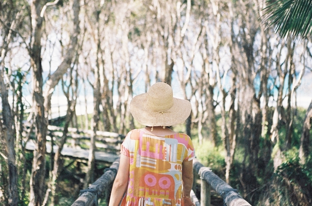 Woman in hat walks toward beach - Australian Stock Image