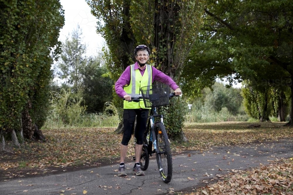Woman in high visability vest standing with bike - Australian Stock Image