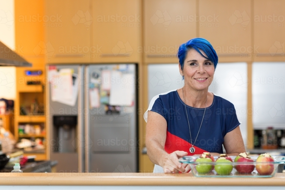 Woman in kitchen with baked apples - Australian Stock Image