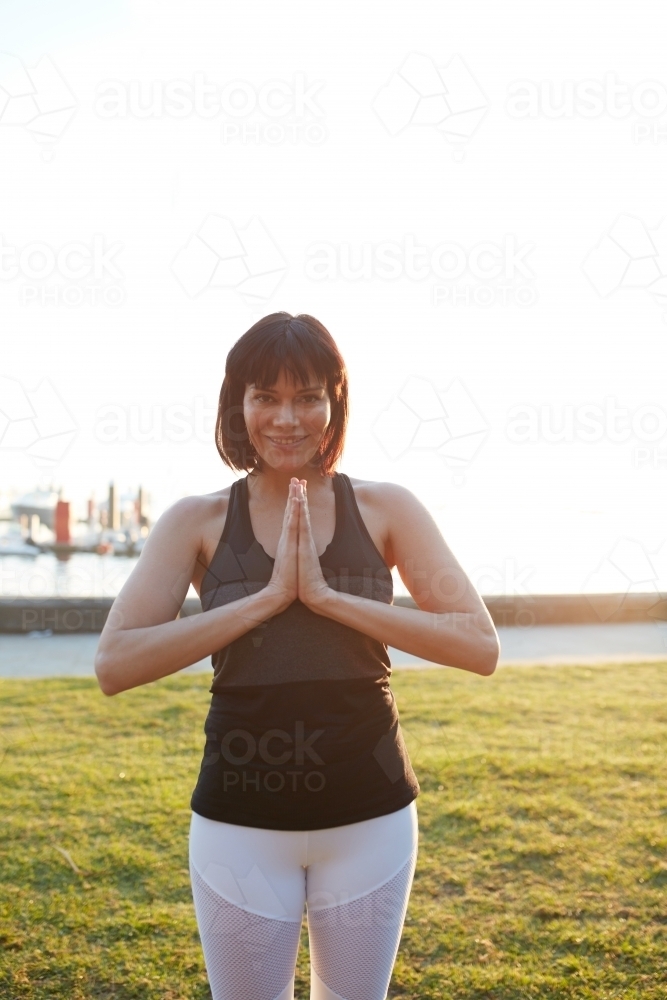 Woman in prayer practicing yoga outdoors - Australian Stock Image