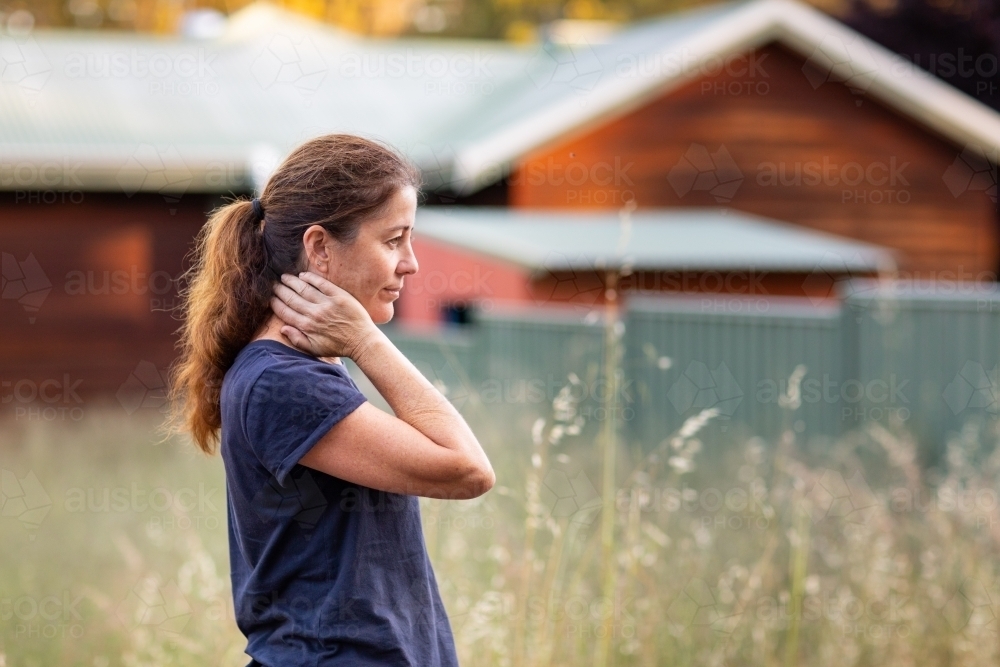 woman in profile outside weatherboard cottage in the country - Australian Stock Image