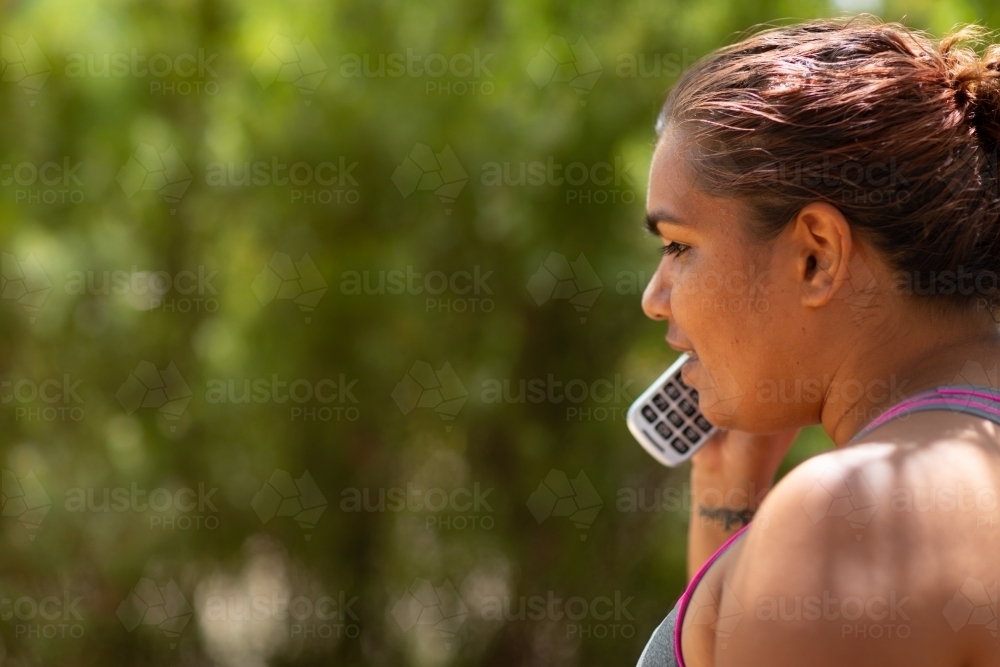 woman in profile talking on phone outdoors - Australian Stock Image