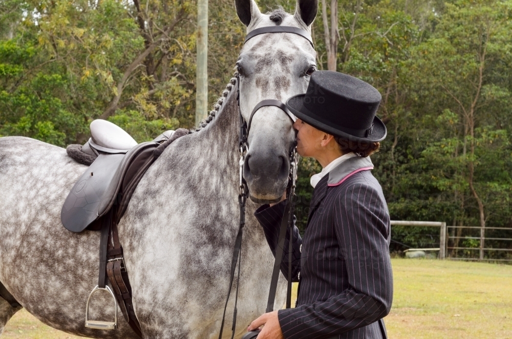 Woman in riding habit nuzzling a dappled grey horse - Australian Stock Image