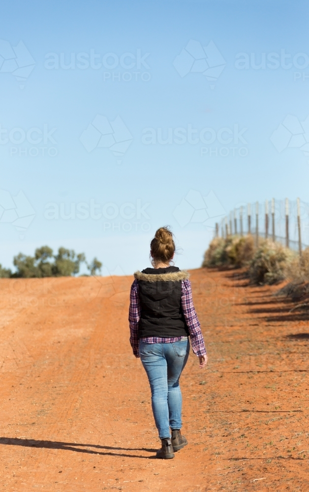 Woman in the outback walking on the dirt road - Australian Stock Image