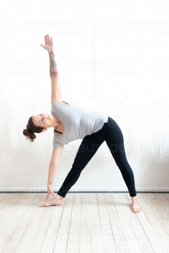 woman in triangle yoga pose in studio - Australian Stock Image