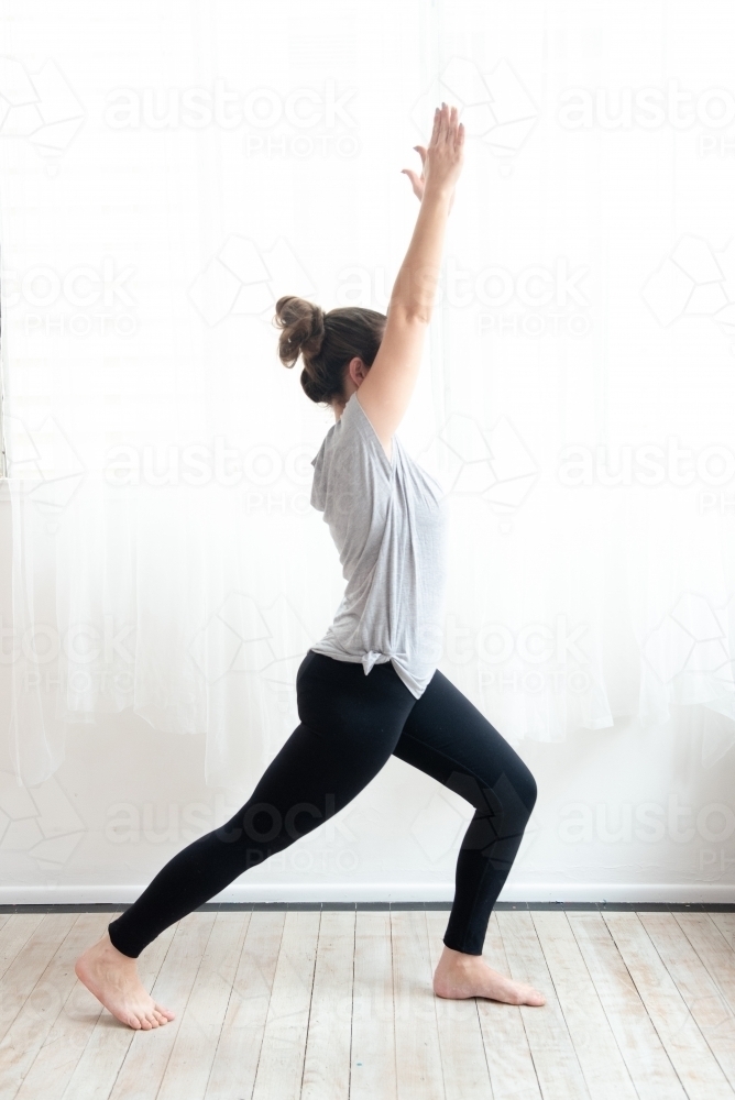 woman in warrior yoga pose in studio - Australian Stock Image