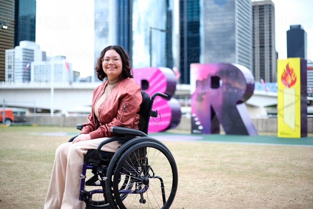 Image of Woman in wheelchair in front of Brisbane sign Austockphoto