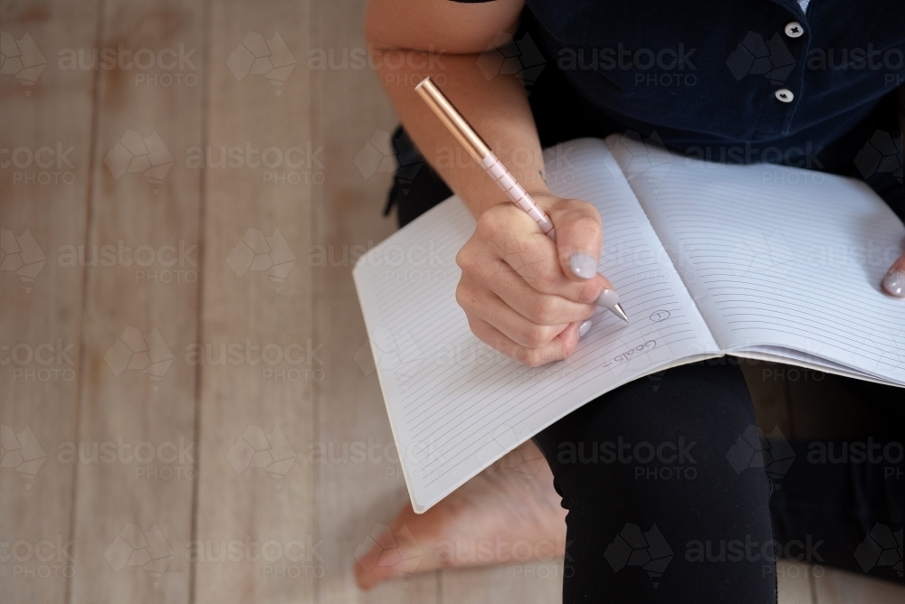 woman journalling bare foot in yoga clothes - Australian Stock Image