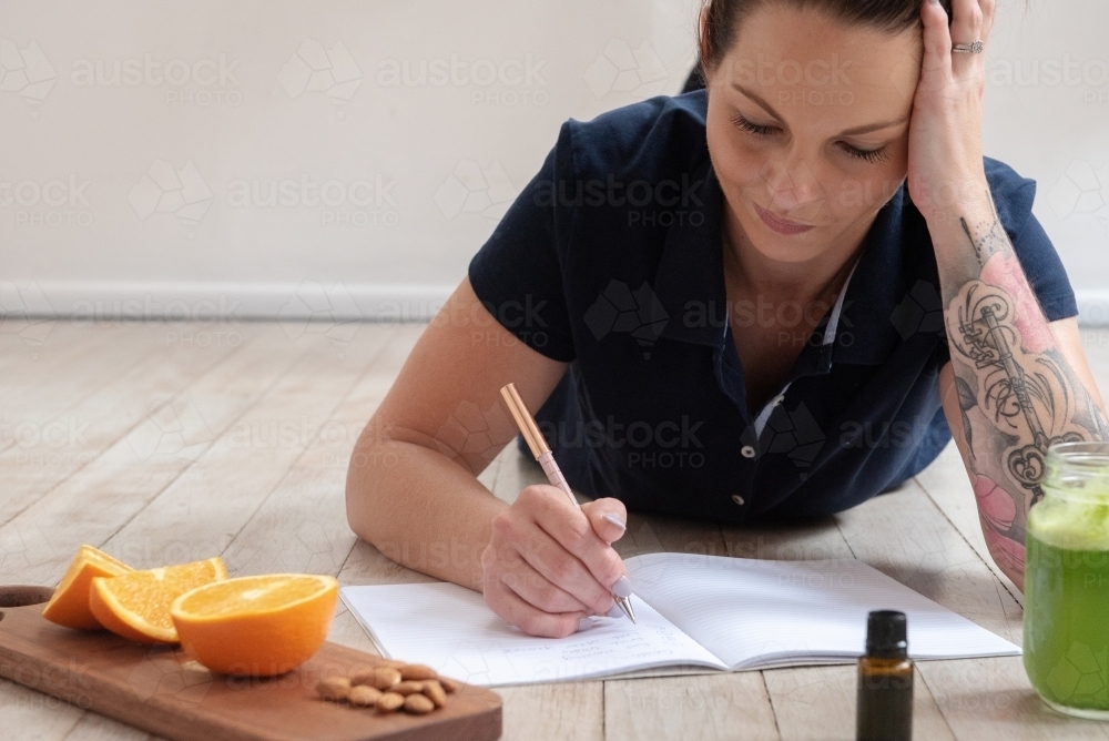 woman journalling with healthy snacks essential oils green juice - Australian Stock Image