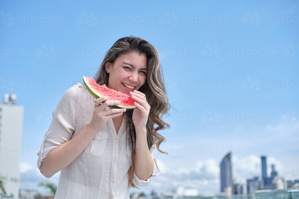 Woman laughing and eating watermelon - Australian Stock Image