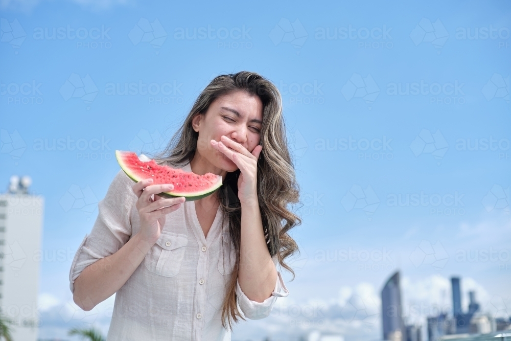 Woman laughing and eating watermelon - Australian Stock Image