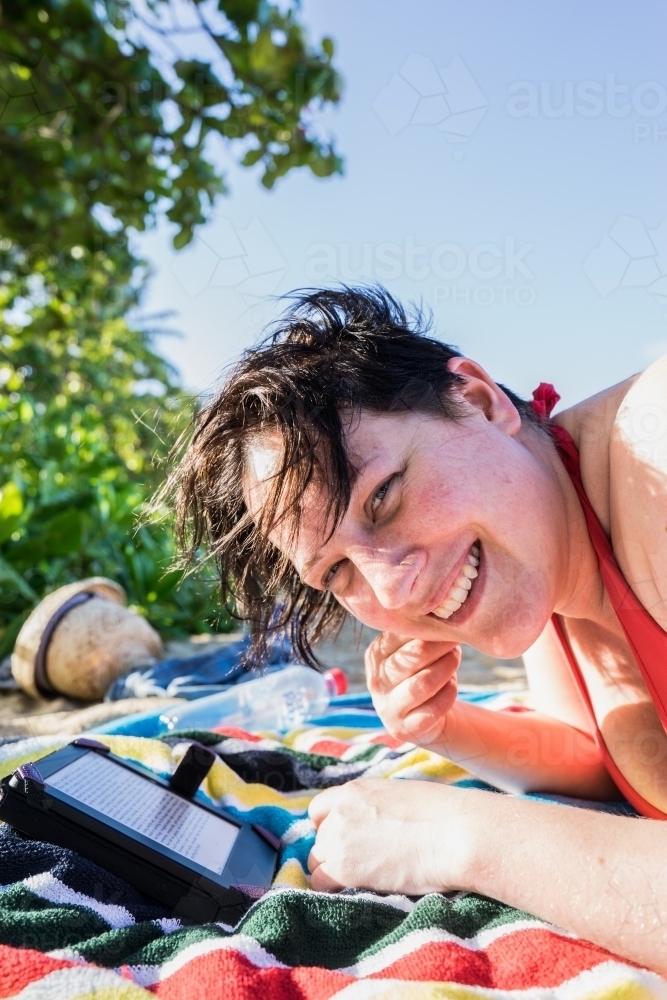 Woman laying on a towel at the beach reading - Australian Stock Image