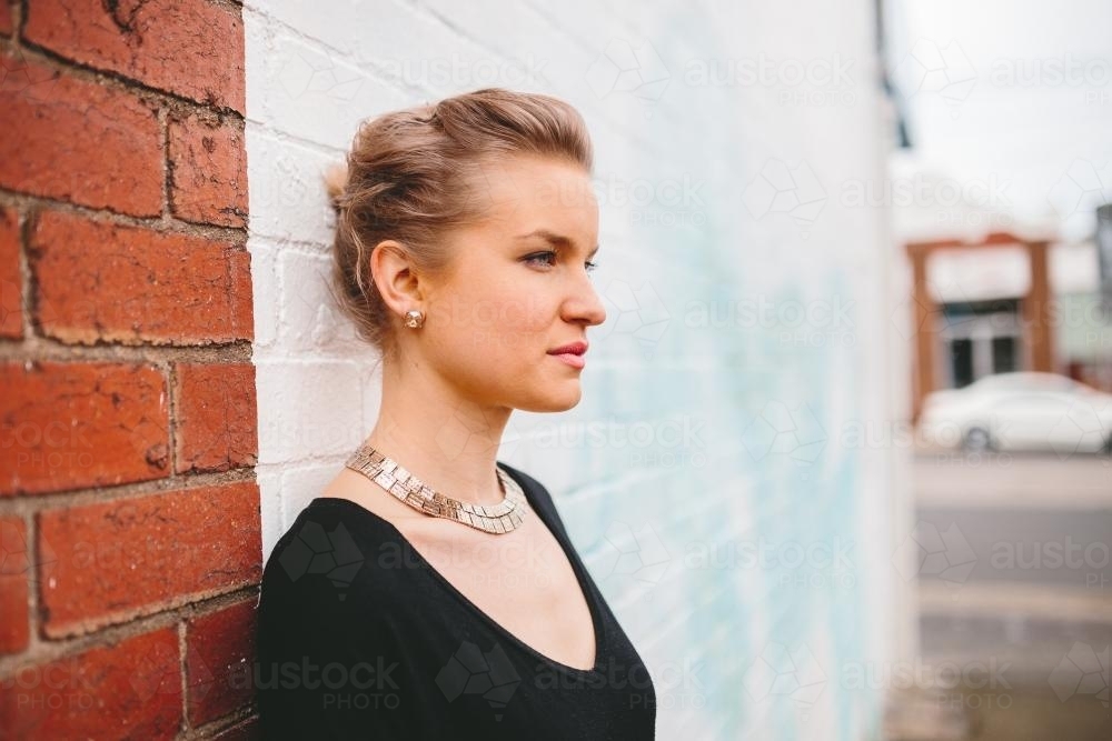 Woman leaning against brick wall - Australian Stock Image