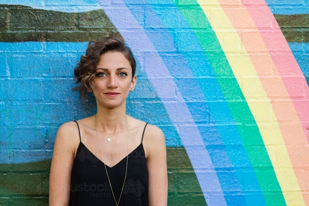 woman leaning against brick wall with rainbow - Australian Stock Image