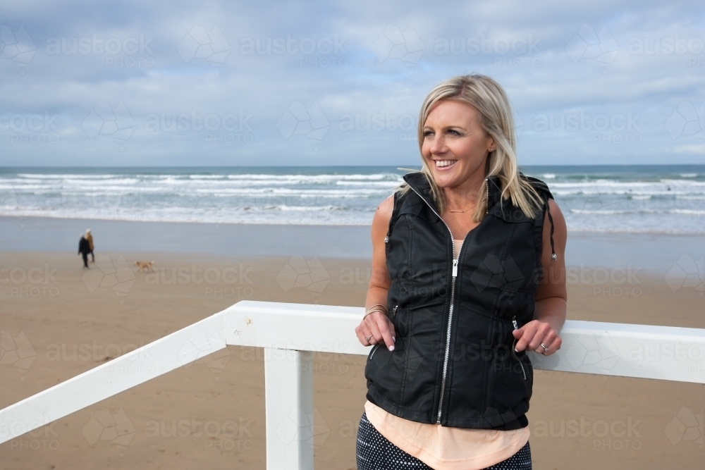 woman leaning on railing at the beach - Australian Stock Image