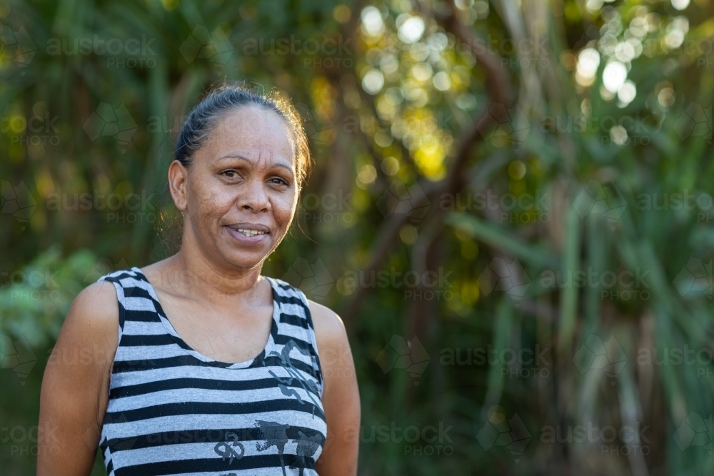 woman looking at camera outdoors with foliage in background - Australian Stock Image