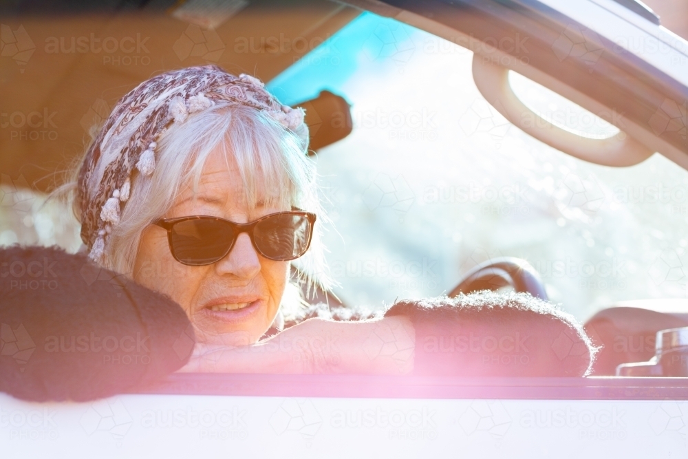 woman looking out car window backlit with sun flare - Australian Stock Image