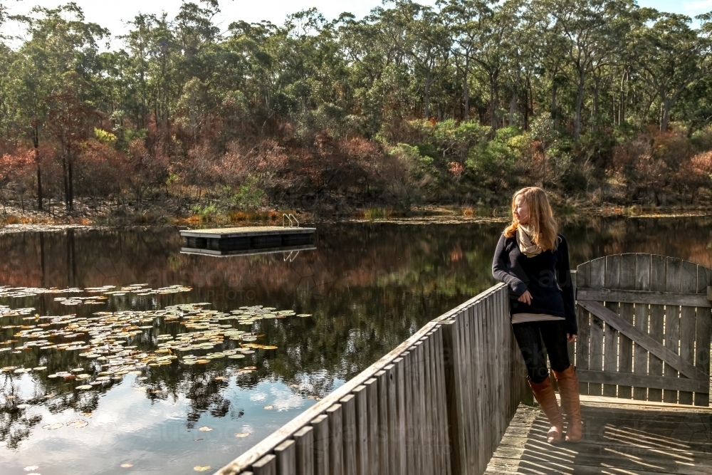 Woman looking over calm lake - Australian Stock Image