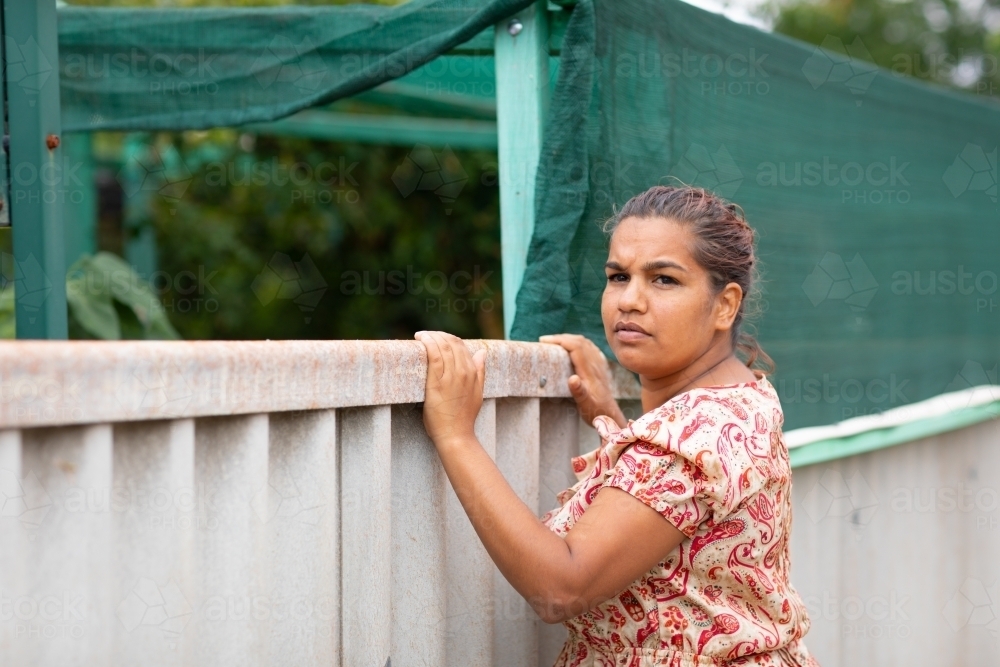 woman looking over fence into neighbour's backyard - Australian Stock Image