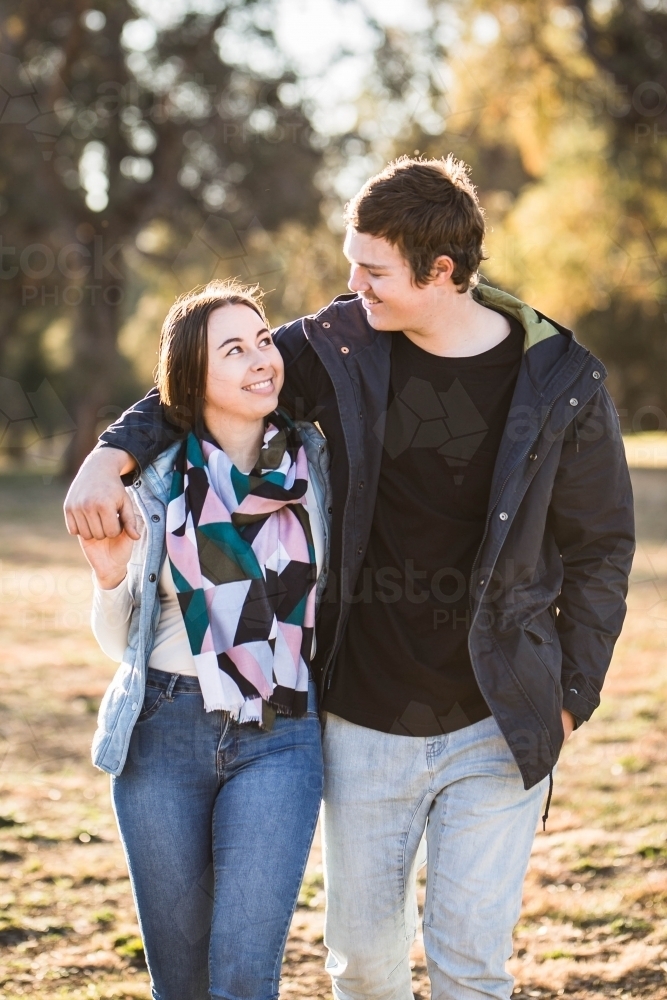 Woman looking up at boyfriend smiling holding hands and walking - Australian Stock Image