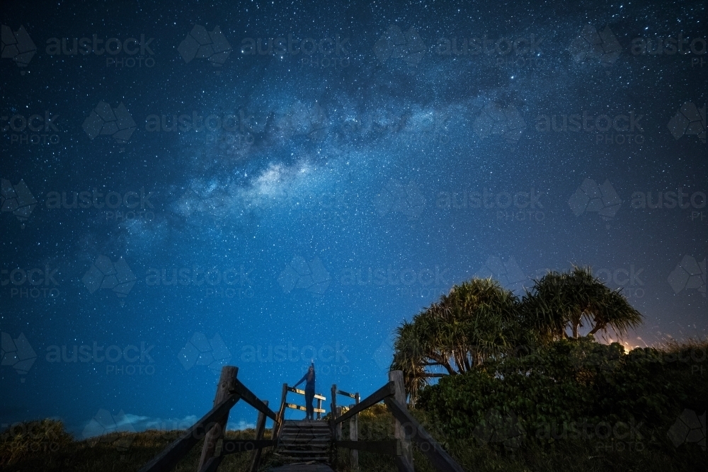 Woman looking up pointing to the Milky Way above her in the sky. - Australian Stock Image