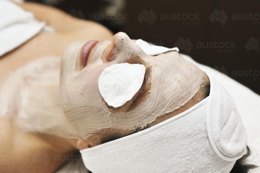 Woman lying down with a clay mask on during a beauty treatment - Australian Stock Image