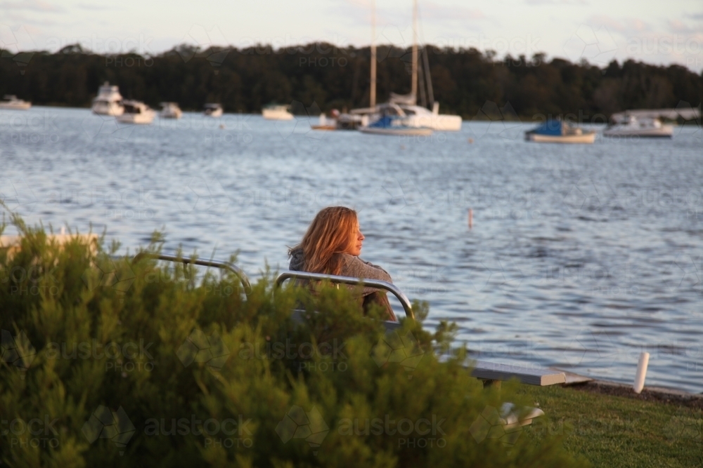 Woman on bench looking out over the water - Australian Stock Image
