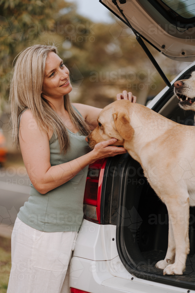 Woman petting her dog in the car boot. - Australian Stock Image