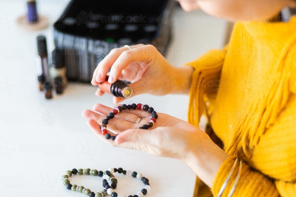 Woman putting essential oils on diffuser bracelet lava stones - Australian Stock Image