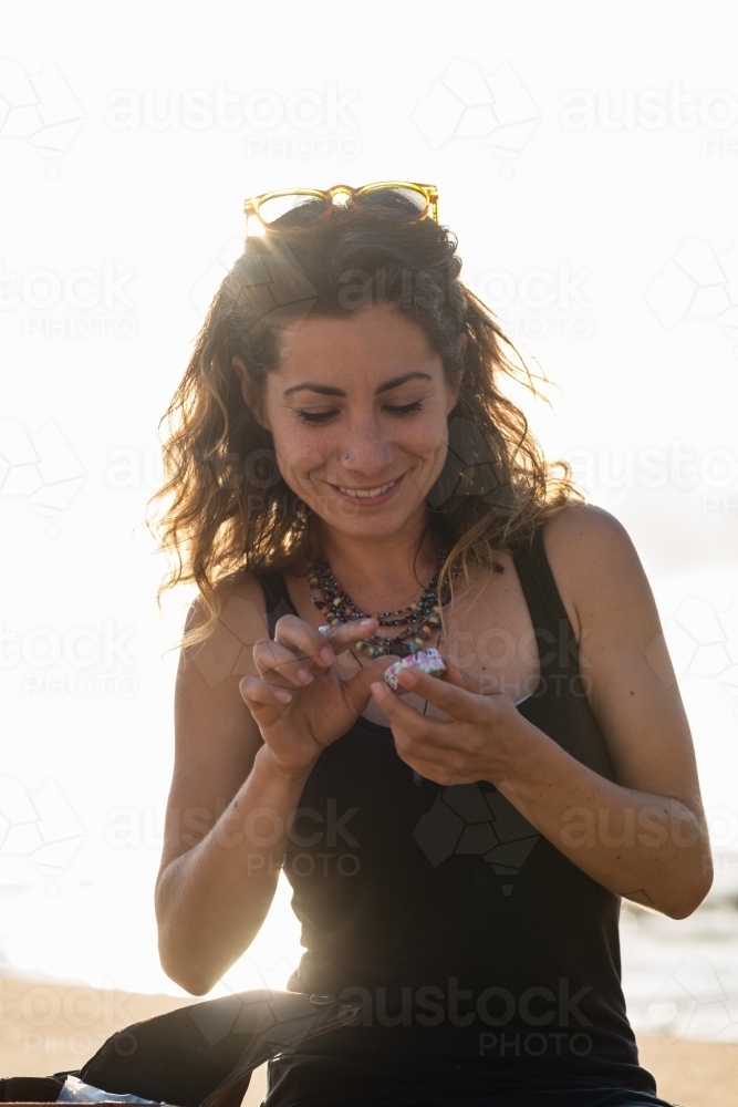 woman putting on lip balm at the beach - Australian Stock Image