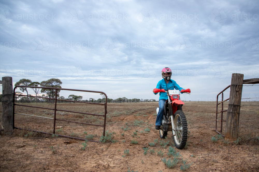 Woman riding motorbike through a gateway - Australian Stock Image