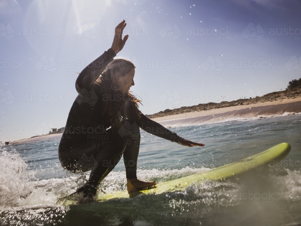 Woman riding wave on surfboard - Australian Stock Image