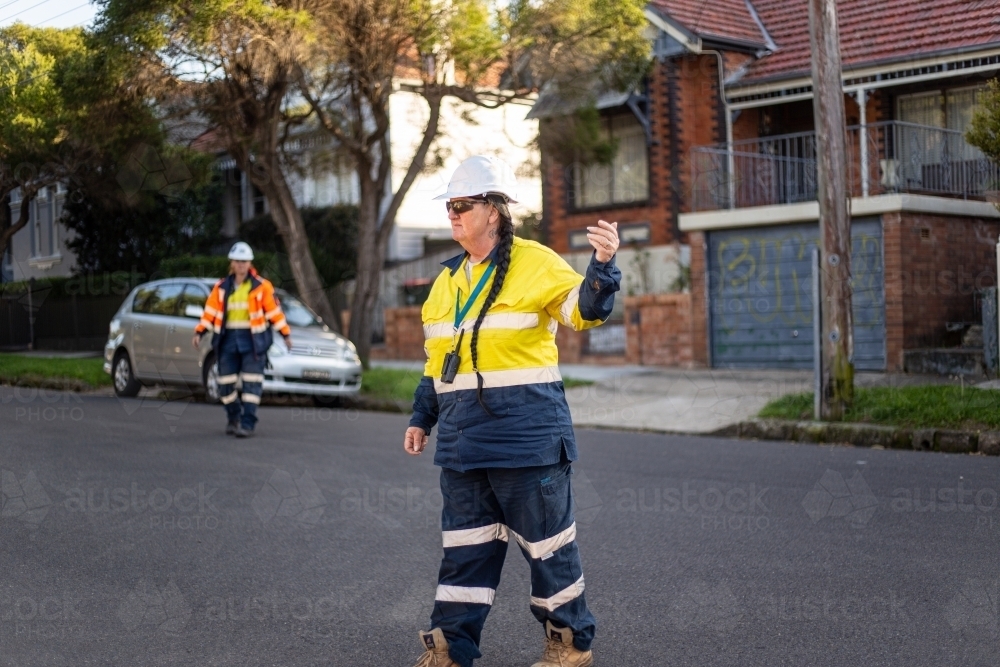 Woman road worker with yellow jacket and white helmet on the road with a long braided hair - Australian Stock Image