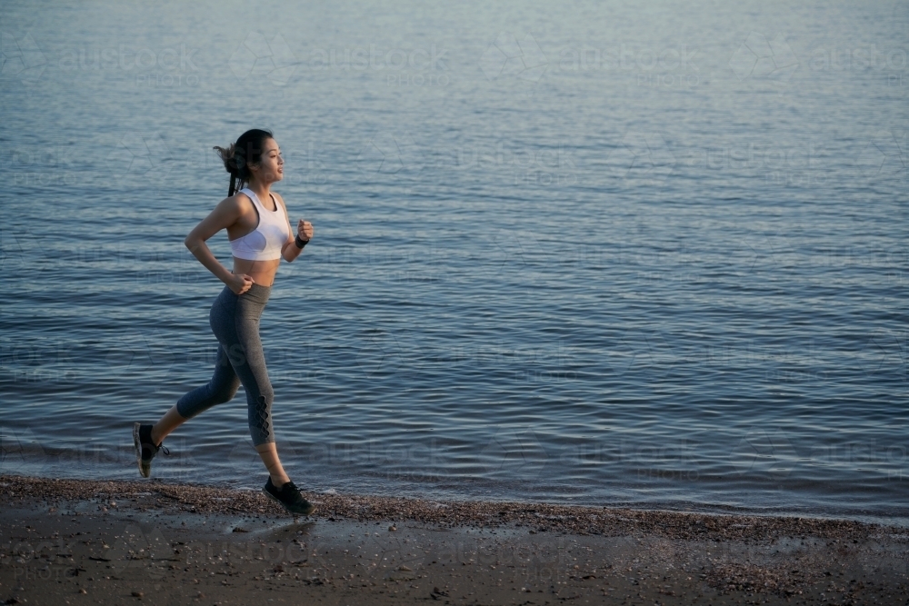 Woman running along waterside for morning exercise - Australian Stock Image