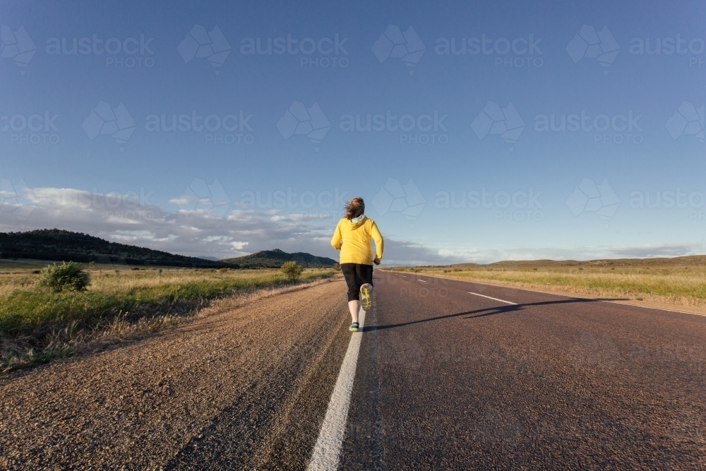 Woman running on a remote country road - Australian Stock Image