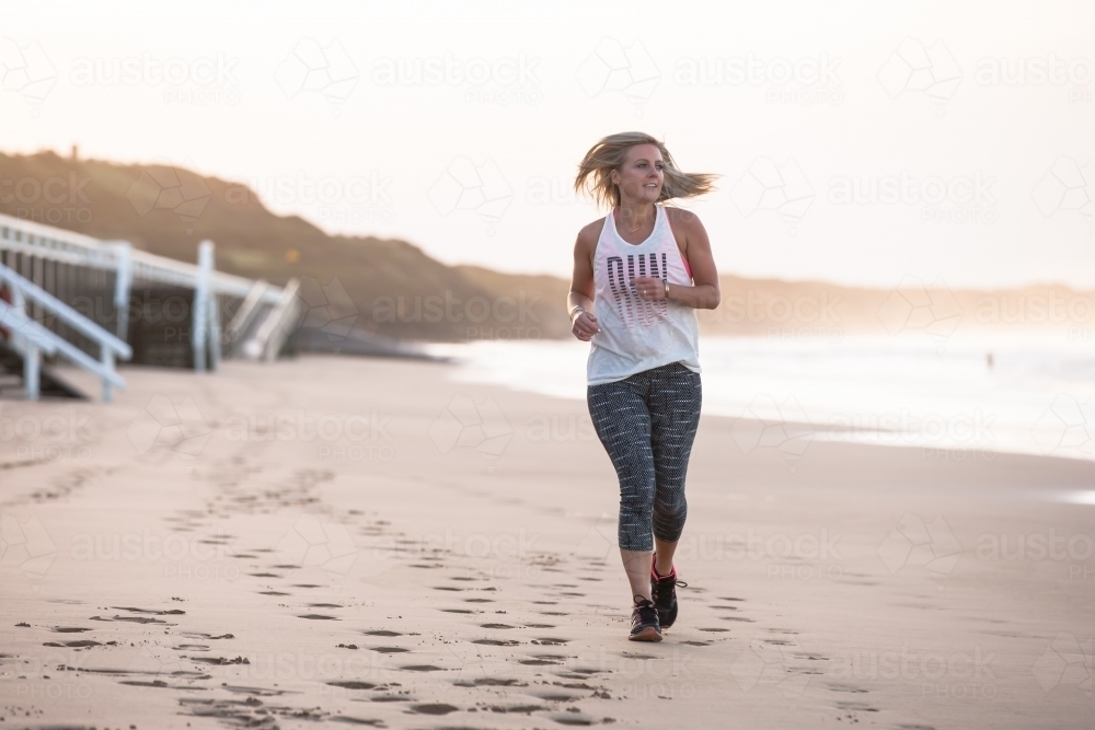 woman running on the beach at dawn - Australian Stock Image