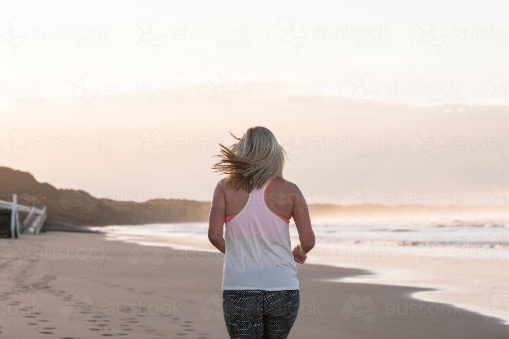 woman running on the beach in the early morning - Australian Stock Image
