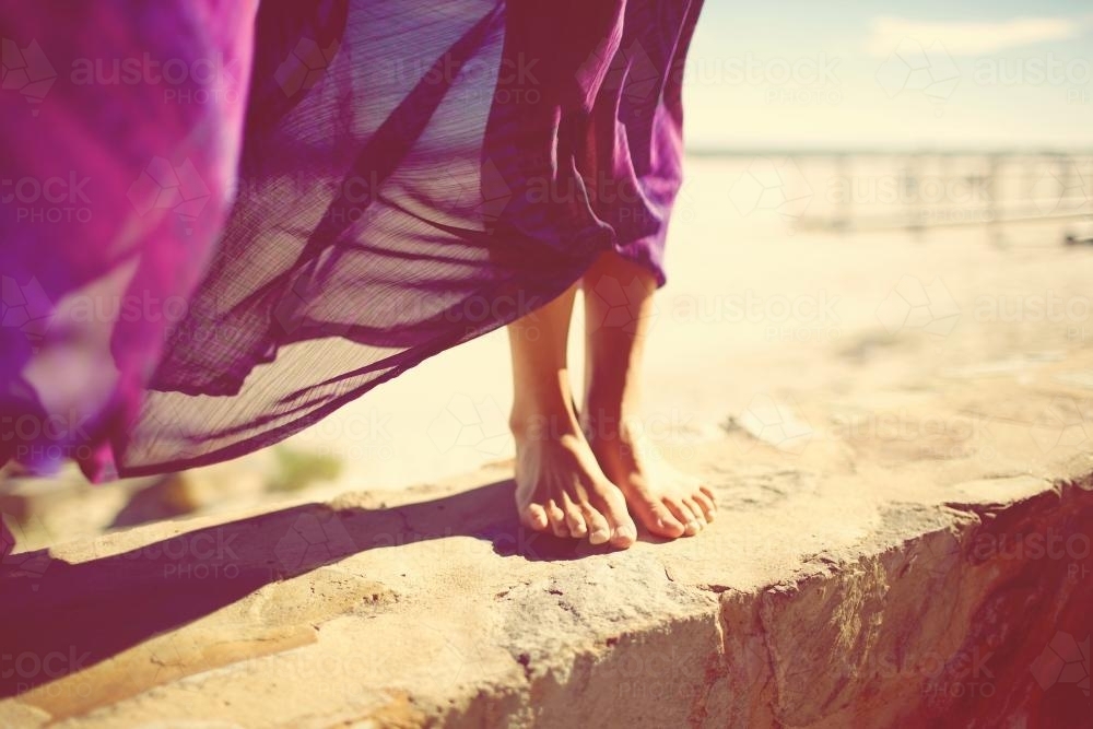 Woman's feet on a wall at a beach - Australian Stock Image