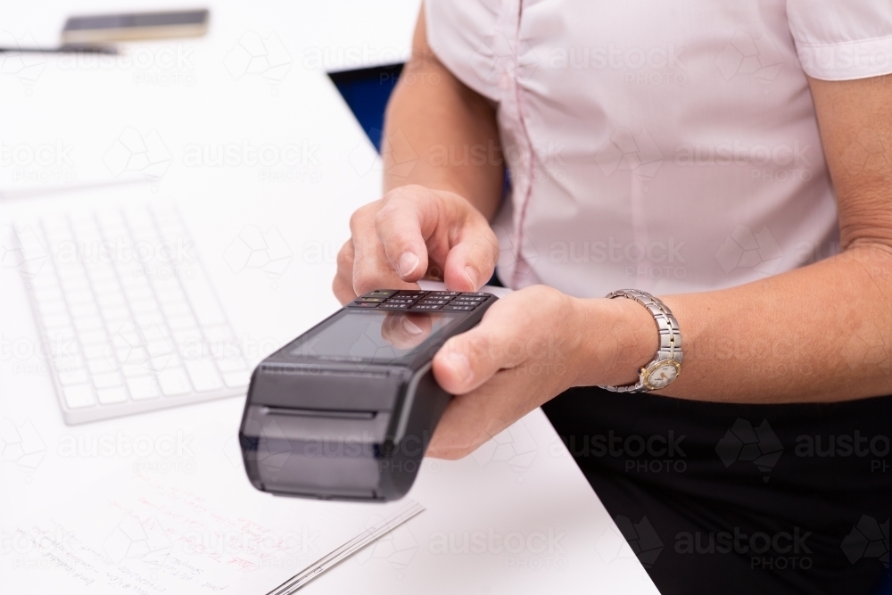 Woman's hands holding EFTPOS terminal to make a payment - Australian Stock Image