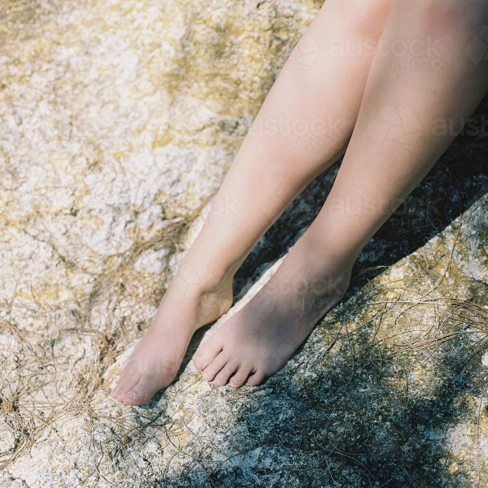 Woman's Naked Legs on Beach Rock - Australian Stock Image